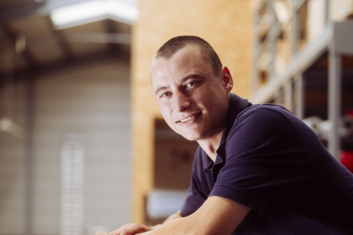 Gregor lehnt sich an ein Geländer in der Halle bei Fritz