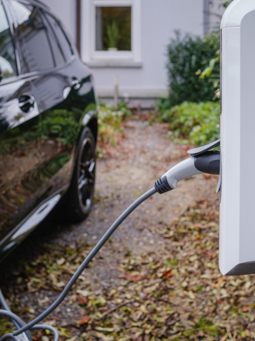 Ein schwarzes Auto lädt an einer Ladesäule im Garten