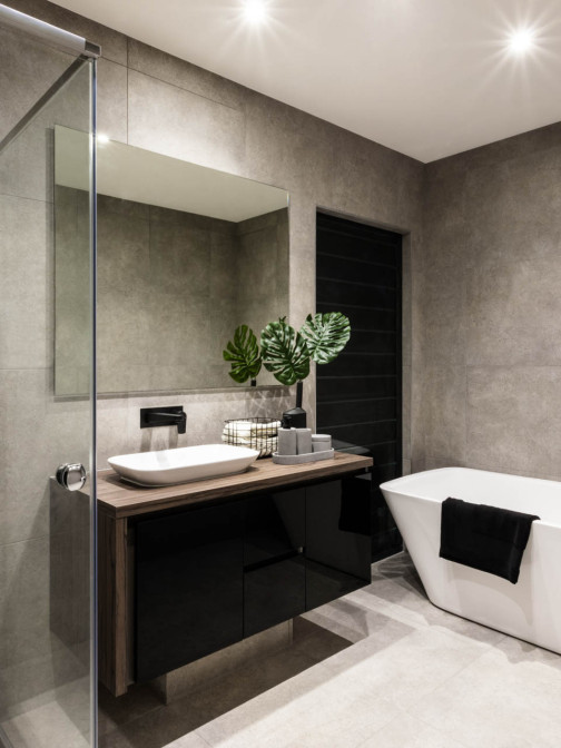 Blick in ein modernes Bad mit grauen Fliesen und freistehender Badewanne