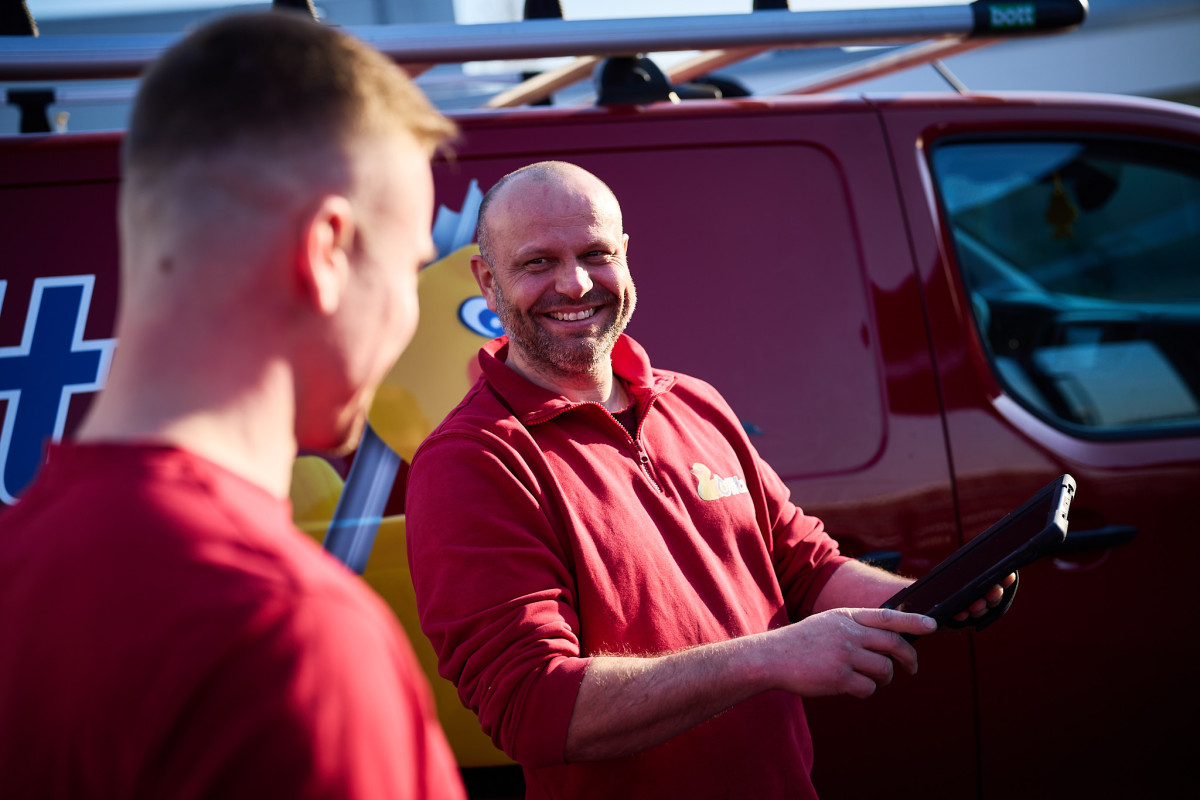 Montageleiter Alexander Schmidt steht mit einem Mitarbeiter im Hof von fritz. Er zeigt ihm etwas auf dem Tablet und beide Lachen.