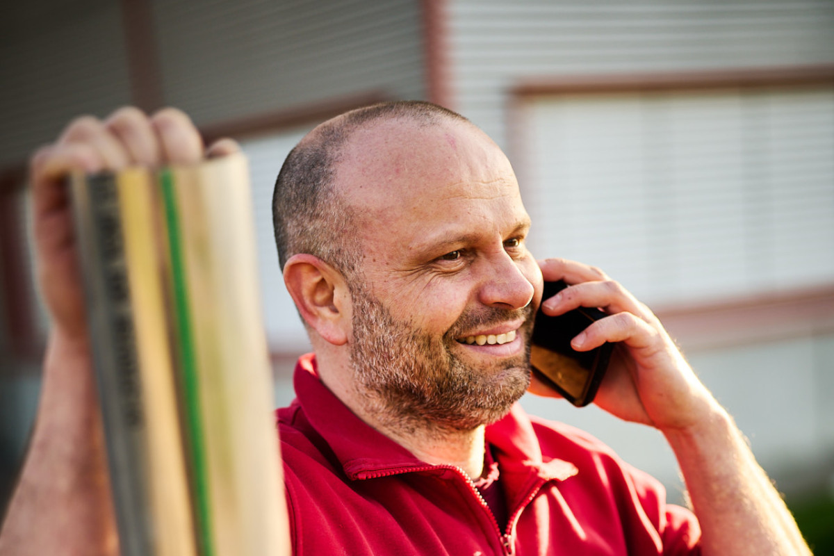 Alexander Schmidt telefoniert, lächelt und lehnt sich lässig an ein Metallrohr. 